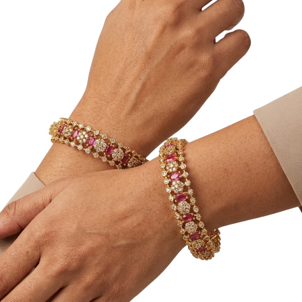 gehna official gold plated bangles featuring ruby oval stones and american diamonds on a woman's wrists.
