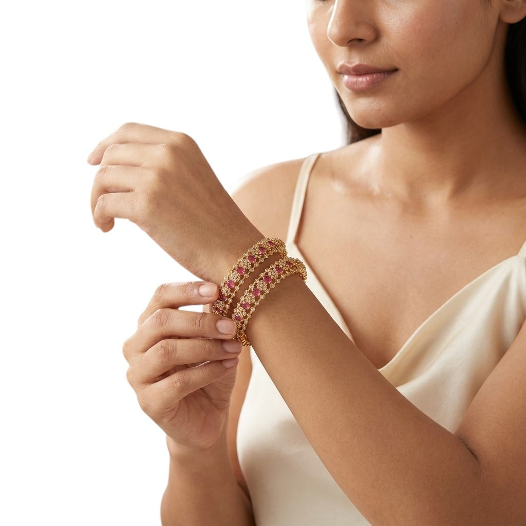 gehna official roselle crown gold plated bangles featuring ruby oval stones and american diamonds on a woman's wrist.
